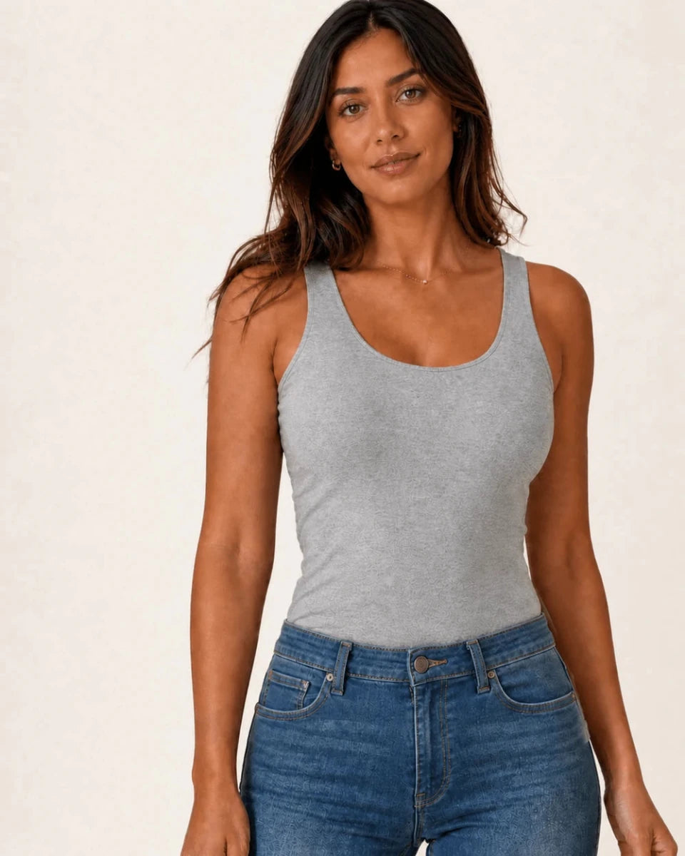 Grey longline tank top styled with blue jeans, three-quarter front view