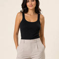 Black ribbed tank top tucked into light stone trousers, front view